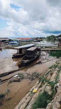 TABATINGA, AMAZONAS, BRAZIL - ÇİRKA Aralık 2019: Amazon nehri üzerindeki Tabatinga iskelesinde kirli kahverengi suyu olan ucuz ahşap kayıklar ve odun parçaları.