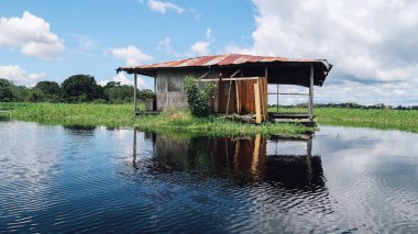 LETICIA, AMAZONAS, COLOMBIA - CRCA Aralık 2019: Güneşli bir günde Amazonas 'ta göl kenarında yüzen terk edilmiş deniz evi.