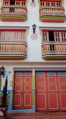 GUATAPE, COLOMBIA - CIRCA JANUARY 2020: Renkli otantik Guatape şehrinde, parke taşı caddelerindeki binaların balkonlarıyla süslenmiş geleneksel benzersiz cepheler.