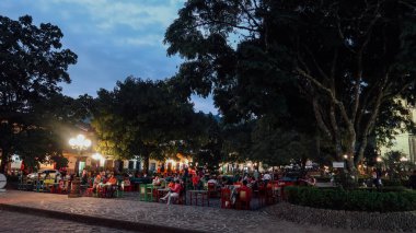 JARDIN, COLOMBIA - CIRCA JANUARY 2020: İnsanlar Antioquia 'nın küçük Jardin kasabasındaki ana meydandaki açık restoran masalarında takılıyor..