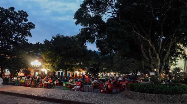 JARDIN, COLOMBIA - CIRCA JANUARY 2020: İnsanlar Antioquia 'nın küçük Jardin kasabasındaki ana meydandaki açık restoran masalarında takılıyor..