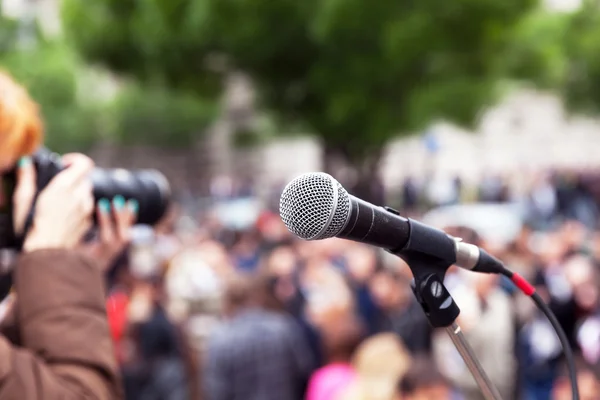 Microphone in focus, blurred female photographer at work in the background — Stock Photo, Image