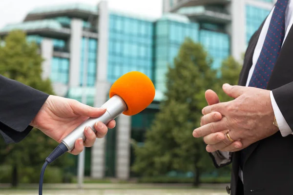 Reporter tenant un micro interviewant un homme d'affaires ou un politicien — Photo