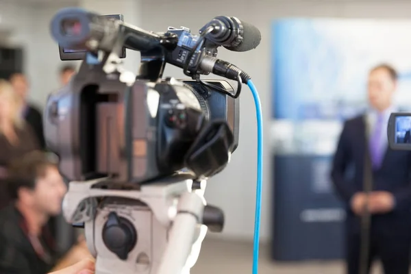 Videokamera im Fokus, verschwommener Sprecher im Hintergrund — Stockfoto