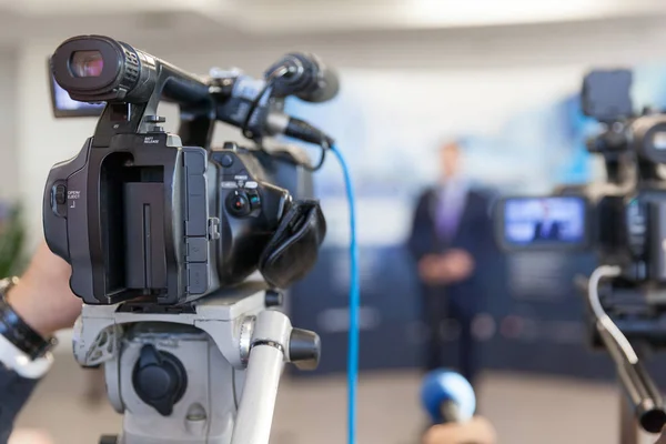 Videokamera im Fokus, unscharfer Sprecher im Hintergrund — Stockfoto