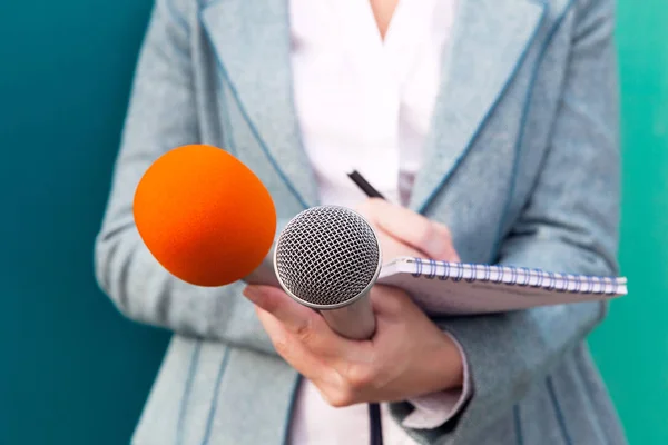 Kvinnlig journalist på presskonferens, skriva anteckningar, hålla mikrofoner — Stockfoto