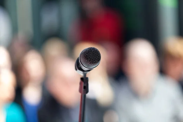 Mikrofon w fokus, niewyraźne publiczność w tle — Zdjęcie stockowe