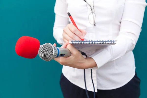 Jornalista feminina na conferência de imprensa, escrevendo notas, segurando microfone — Fotografia de Stock