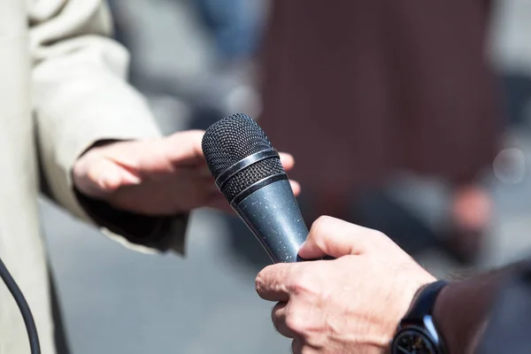 Journalist holding a microphone conducting an TV or radio interview — Stock Photo, Image
