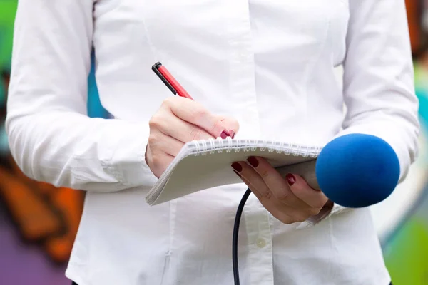 Journaliste féminine lors d'une conférence de presse, écrivant des notes, tenant un microphone — Photo