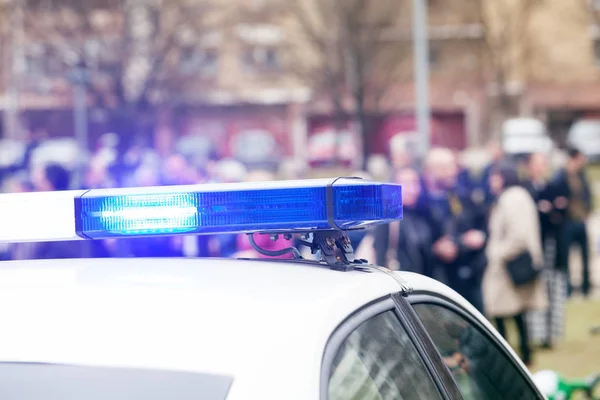 Auto della polizia lampeggiante luci a fuoco, folla offuscata in background — Foto Stock