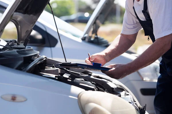 Automatisk mekaniker kontrollera bil motor och skriva på Urklipp — Stockfoto