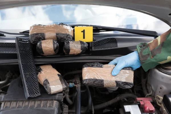 Policjant posiadający pakiet narkotyków, odkryta w silniku komora — Zdjęcie stockowe