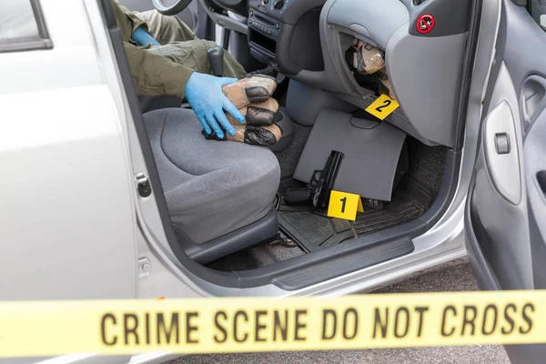 Policial segurando pacotes de drogas encontrados em compartimento secreto de um carro — Fotografia de Stock