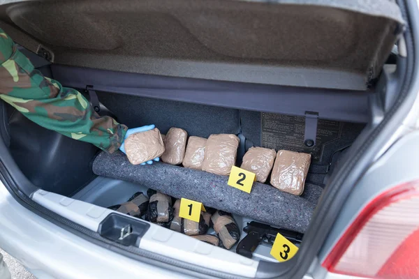 Agente di polizia con un pacco di droga trovato nel bagagliaio di un'auto — Foto Stock