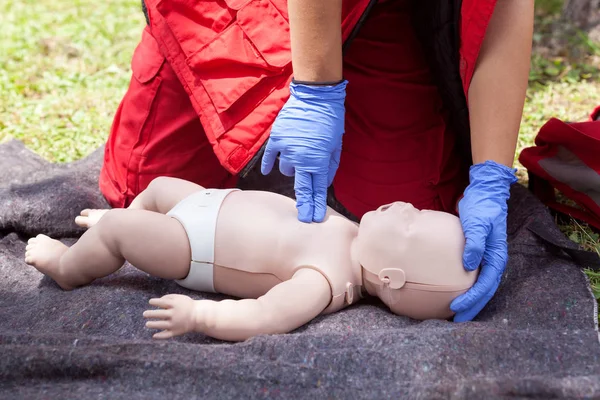 Paramedic performing CPR on baby dummy with two-finger chest compression — Stock Photo, Image