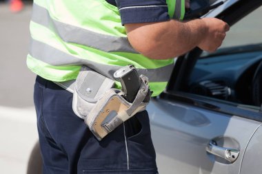 Polis memuru trafik kontrolü sırasında bir araç sürücüsü sürücü belgesi denetliyor