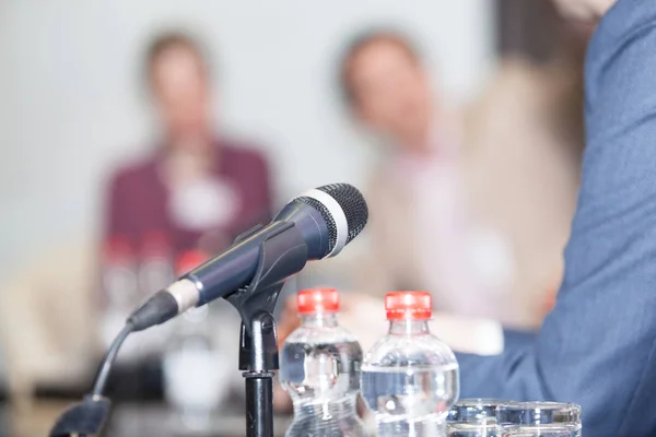 Micrófono enfocado contra personas borrosas en el evento de mesa redonda — Foto de Stock