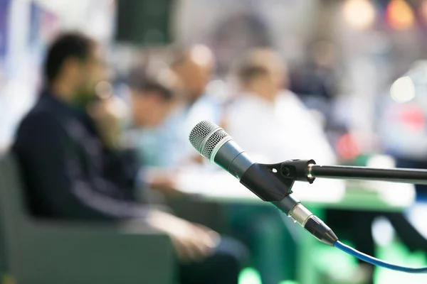 Microphone in focus against blurred people at roundtable event — Stock Photo, Image