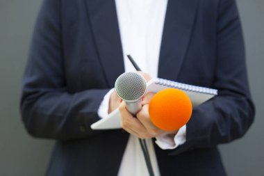 Basın konferansında elinde mikrofon, elinde notlar tutan gazeteci ya da gazeteci.