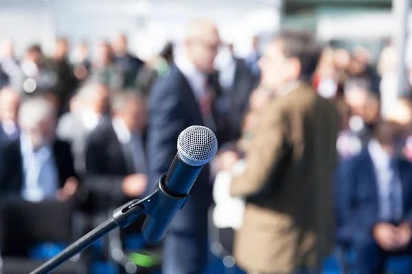 Forretningskonferanse eller bedriftspresentasjon. Mikrofon i fokus mot tåkete publikum . – stockfoto