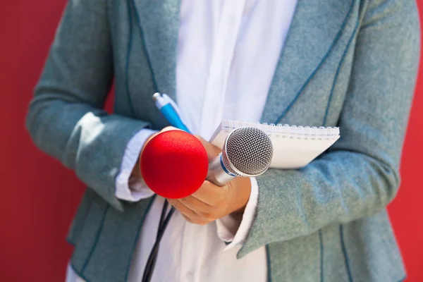 Female reporter at press conference, writing notes, holding microphone — Stock Photo, Image