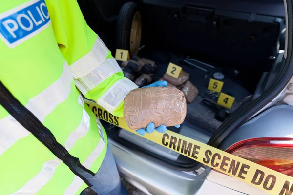Agente di polizia con un pacco di droga trovato nel bagagliaio di un'auto — Foto Stock