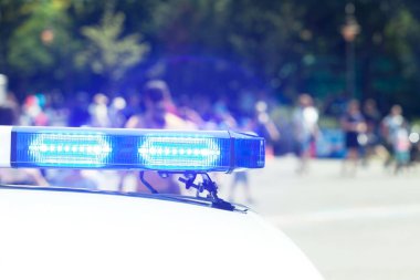 Police car flashing lights in focus, blurred people in the background. Law enforcement concept.