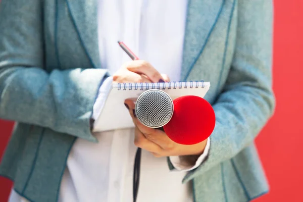 Woman journalist or reporter at news conference, writing notes, holding microphone. Journalism concept. — ストック写真