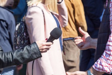 Medya röportajı yapan bir muhabir mikrofon tutuyor