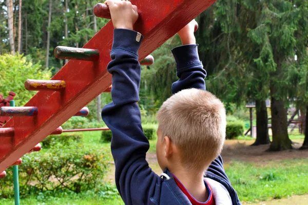Мальчик на горизонтальной полосе на детской площадке . — стоковое фото