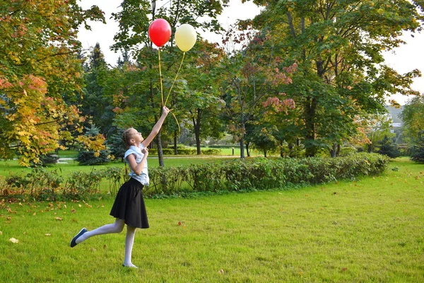 Mädchen lässt im Herbst Luftballons in den Himmel steigen. — Stockfoto