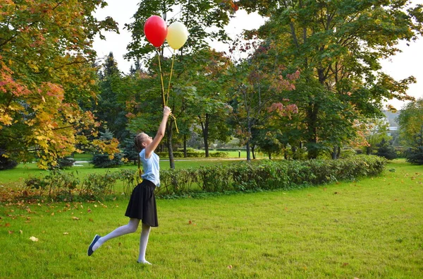 Mädchen lässt im Herbst Luftballons in den Himmel steigen. — Stockfoto