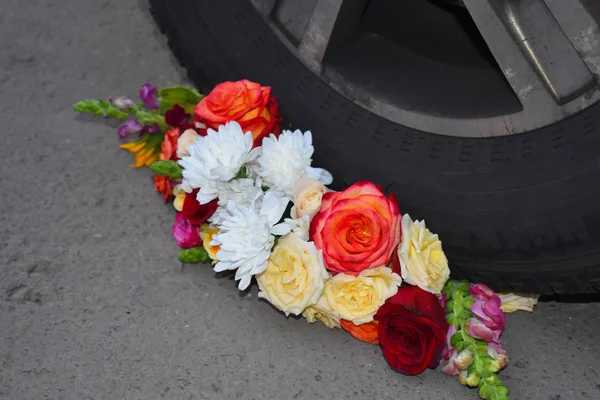 Kytice květin pod volantem auta. Rozdrcená a zlomená láska. — Stock fotografie