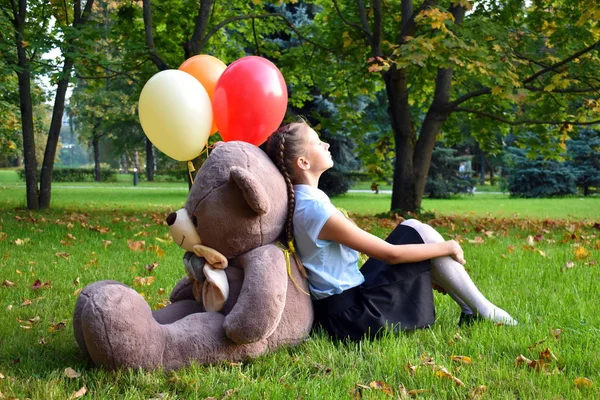 Menina triste com grande ursinho de pelúcia e balões no parque. Problemas adolescentes na escola . — Fotografia de Stock