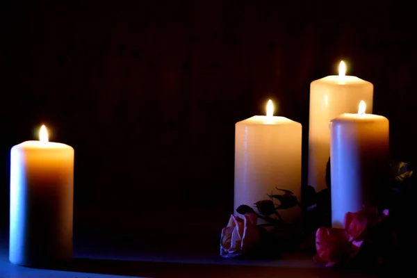 Funeral memorial background. Farewell condolences wallpaper. Day of memory and sorrow. Remember and mourn. Several white candles with flowers on black. — Stockfoto