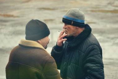 Sonbaharda sokakta sigara içen iki fakir adam