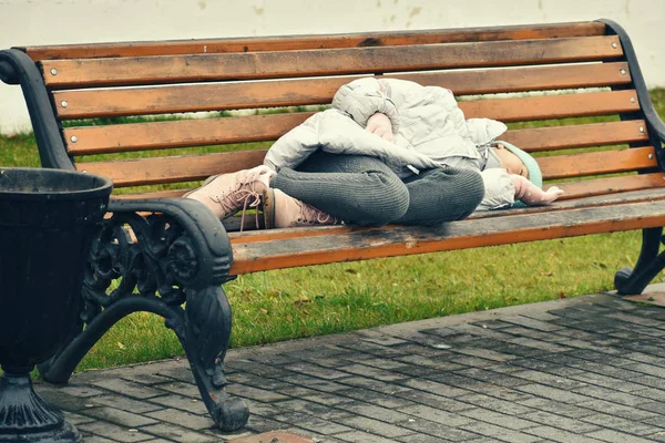 Una vagabunda durmiendo en un banco. Chica adolescente se encuentra en el banco en otoño . — Foto de Stock