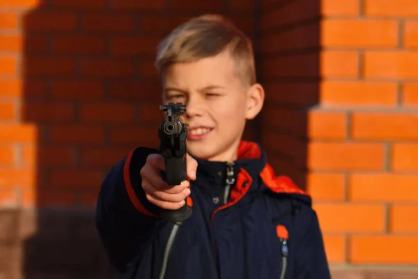 Niño con armas peligrosas. El chico dispara un arma. Adolescente con un arma. Niño aprender a disparar . — Foto de Stock