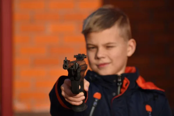 Niño con armas peligrosas. El chico dispara un arma. Adolescente con un arma. Niño aprender a disparar . — Foto de Stock