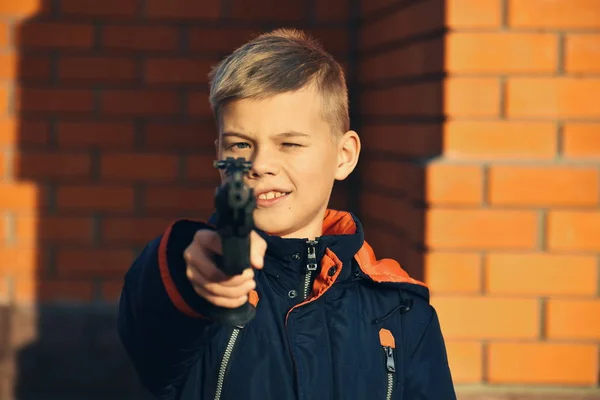 Barn med farliga vapen. Pojken skjuter. Tonåring med pistol. Barn lär sig att skjuta. — Stockfoto