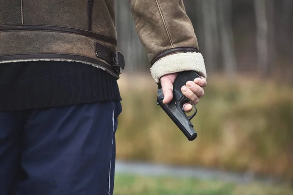 Un hombre con un arma afuera. El criminal dispara una pistola. Bandido oh carretera — Foto de Stock