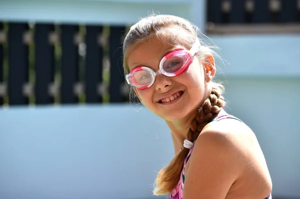 Happy girl swims in the pool. Portrait of a girl in swimming goggles. — ストック写真