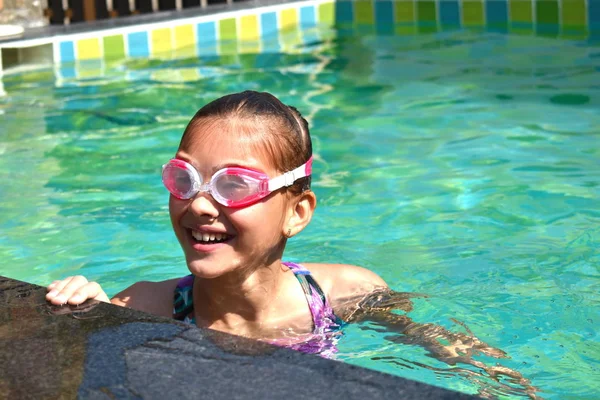 Portrait of a girl in swimming goggles. Happy girl swims in the pool — ストック写真