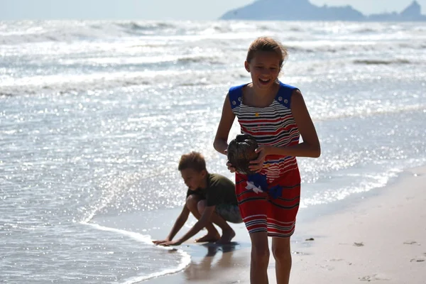Menina segurando um coco. Um adolescente corre ao longo da costa . — Fotografia de Stock