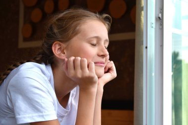 Çocuk kız pencereye yaslandı. Çocuk sabah keyfine bakıyor..