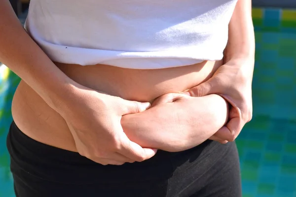 Una capa de grasa en el abdomen femenino. El concepto de pérdida de peso y dieta. Chica sosteniendo su vientre gordo . —  Fotos de Stock