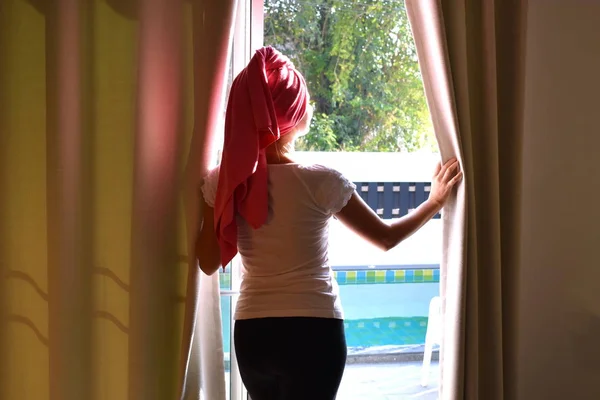 Dziewczyna w ręczniku wygląda przez okno. Kobieta po kąpieli. — Zdjęcie stockowe