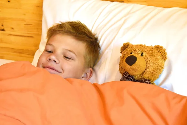 Leuke jongen in bed met een speeltje. Het kind slaapt in een teddybeer.. — Stockfoto