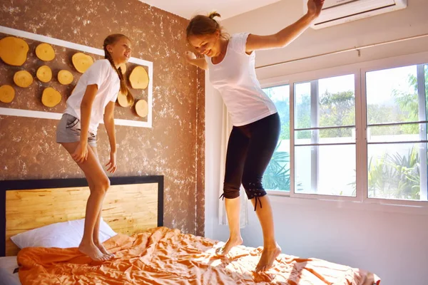 A mãe e a filha estão a saltar para a cama. Mãe alegre e feliz — Fotografia de Stock